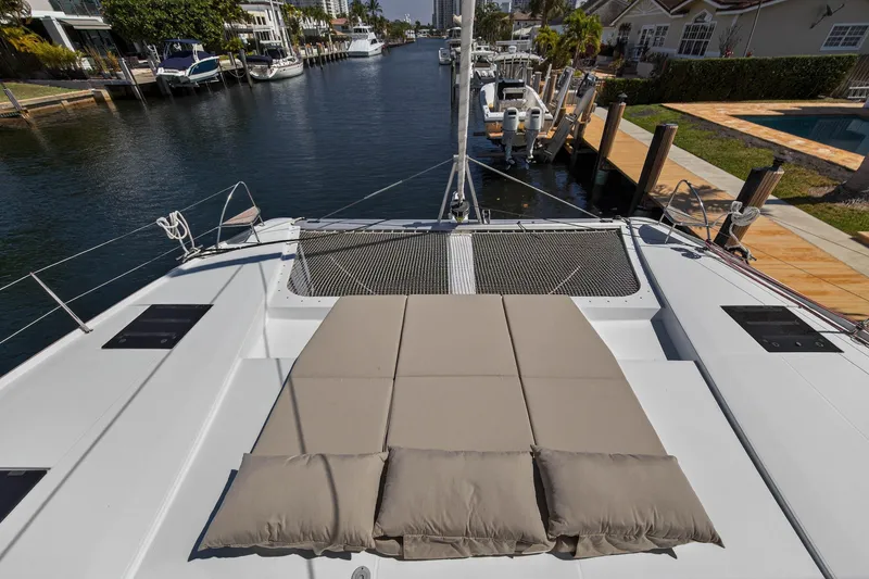 Slide: The Image of 2022 Fountaine Pajot Tanna 47 catamaran with sunbathing area, docked in a scenic marina. - 47