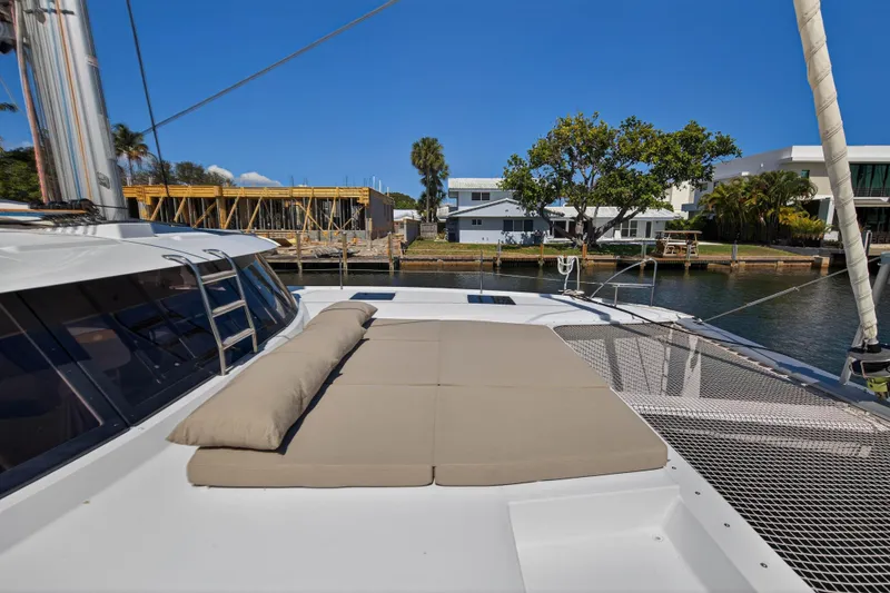 Slide: The Image of 2022 Fountaine Pajot Tanna 47 catamaran with sunbathing area, docked near waterfront homes. - 51
