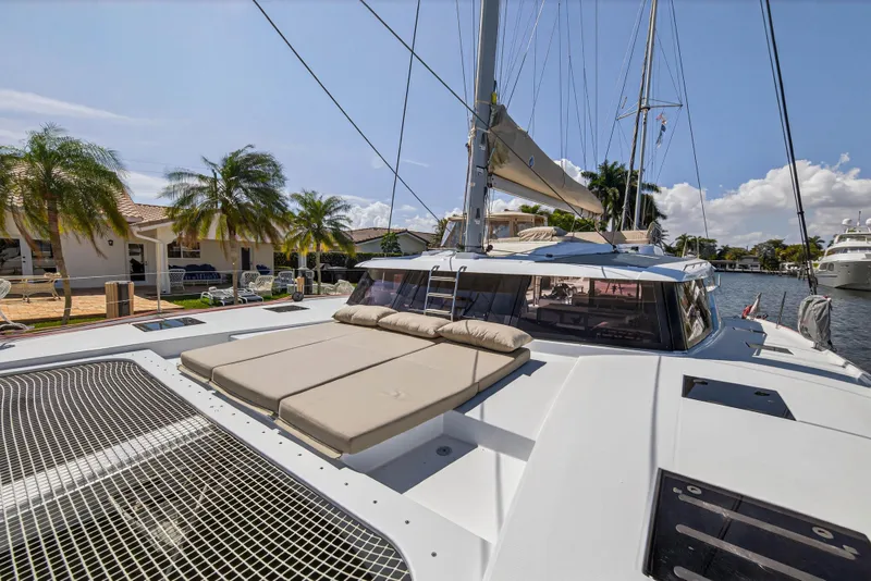 Slide: The Image of 2022 Fountaine Pajot Tanna 47 catamaran with sunbathing area, docked near palm trees. - 54