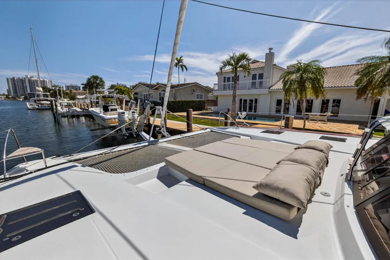 Slide: The Image of 2022 Fountaine Pajot Tanna 47 catamaran docked near waterfront homes, featuring spacious deck. - 56