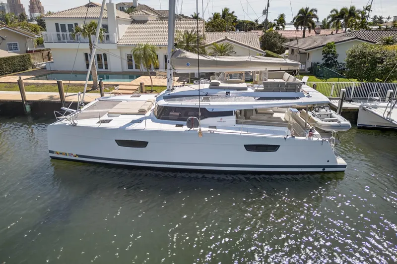 Slide: The Image of 2022 Fountaine Pajot Tanna 47 catamaran docked by waterfront homes. - 6