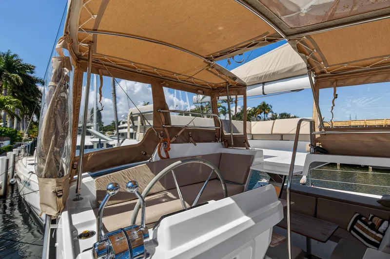 Slide: The Image of 2022 Fountaine Pajot Tanna 47 yacht helm with canopy, docked by palm trees. - 60