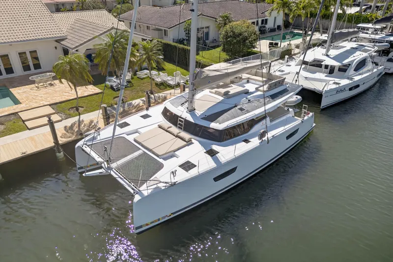 Slide: The Image of 2022 Fountaine Pajot Tanna 47 catamaran docked by waterfront homes. - 7