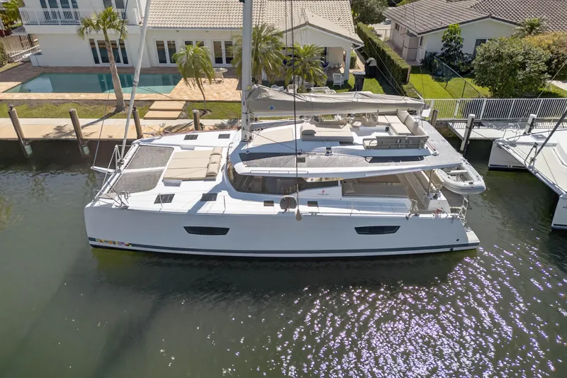 Slide: The Image of 2022 Fountaine Pajot Tanna 47 catamaran docked by waterfront home. - 8