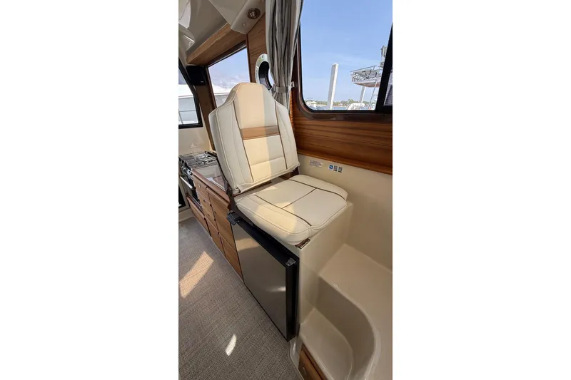 Slide: The Image of Interior of 2026 Ranger Tugs R-27, featuring a comfortable seat and compact kitchenette. - 18