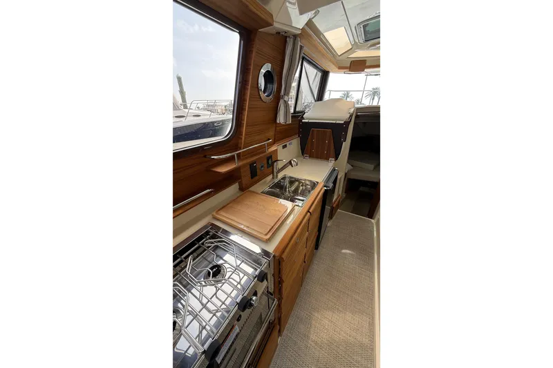 Slide: The Image of 2026 Ranger Tugs R-27 interior with modern kitchen, wood finish, and compact design. - 19