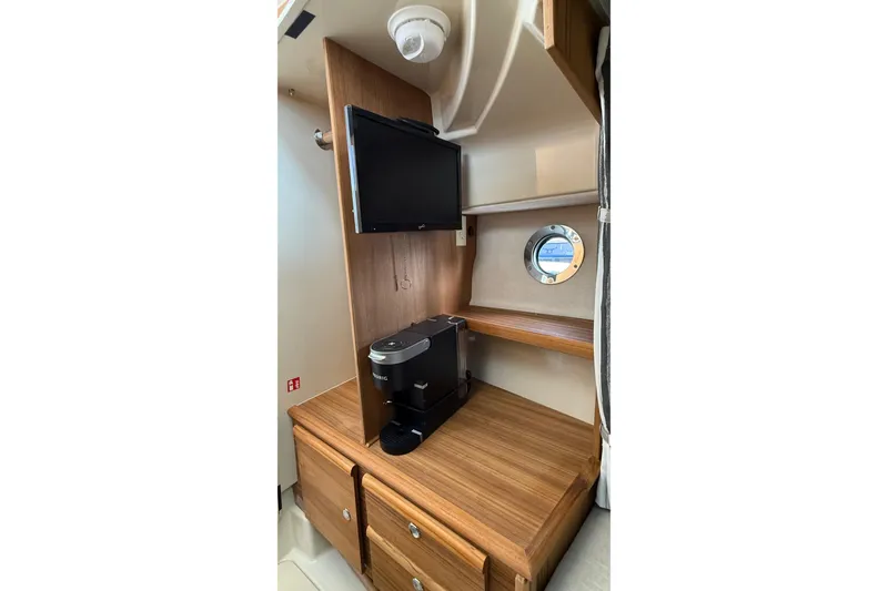 Slide: The Image of Interior of 2026 Ranger Tugs R-27 with TV, coffee maker, and porthole window. - 25