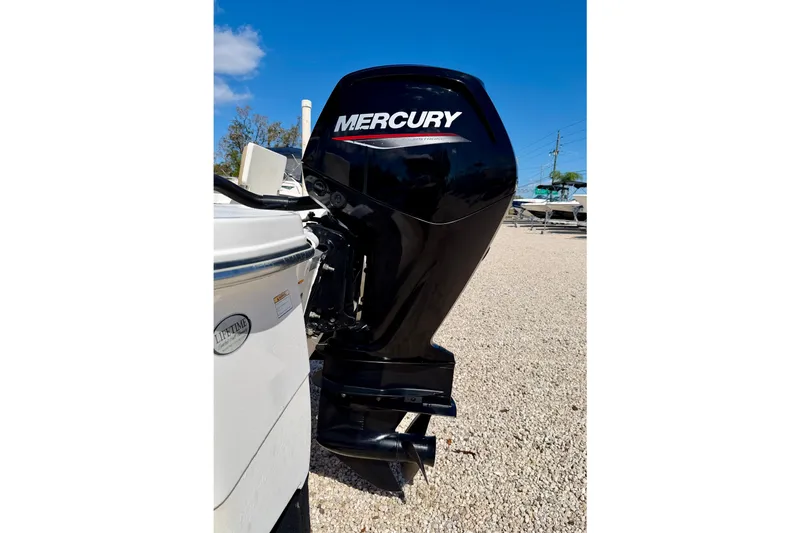 Slide: The Image of 2021 NauticStar 191 Hybrid with Mercury outboard engine, parked on gravel. - 28