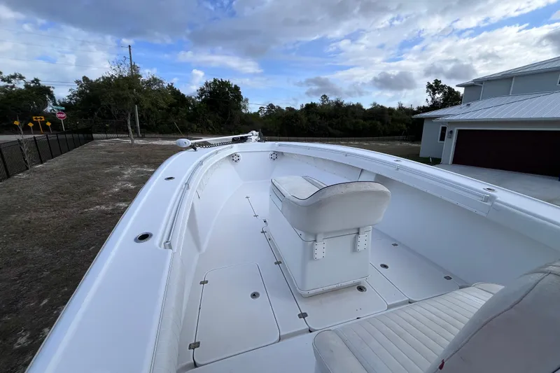 Slide: The Image of 2004 Yellowfin 36 Offshore boat with white seating, parked outdoors under a cloudy sky. - 17