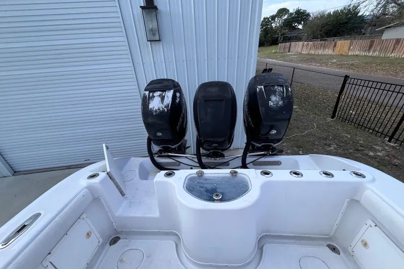 Slide: The Image of 2004 Yellowfin 36 Offshore boat with triple outboard engines, docked near a metal building. - 29