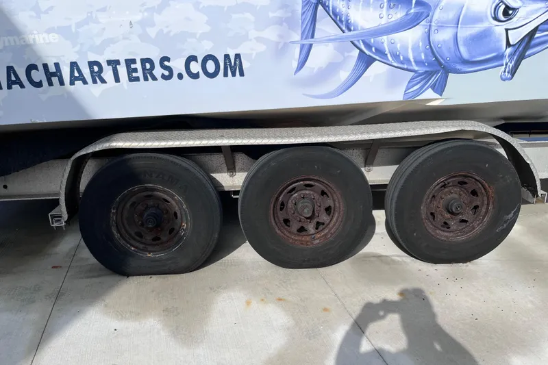 Slide: The Image of Trailer with three wheels, advertising a fishing charter, beside a 2004 Yellowfin 36 Offshore boat. - 47