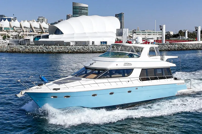 Slide: The Image of 2003 Carver 570 Voyager Pilothouse yacht cruising near a modern waterfront cityscape. - 5