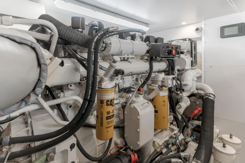 Slide: The Image of Engine room of 2006 West Bay 64 yacht, featuring Caterpillar components and intricate piping. - 16
