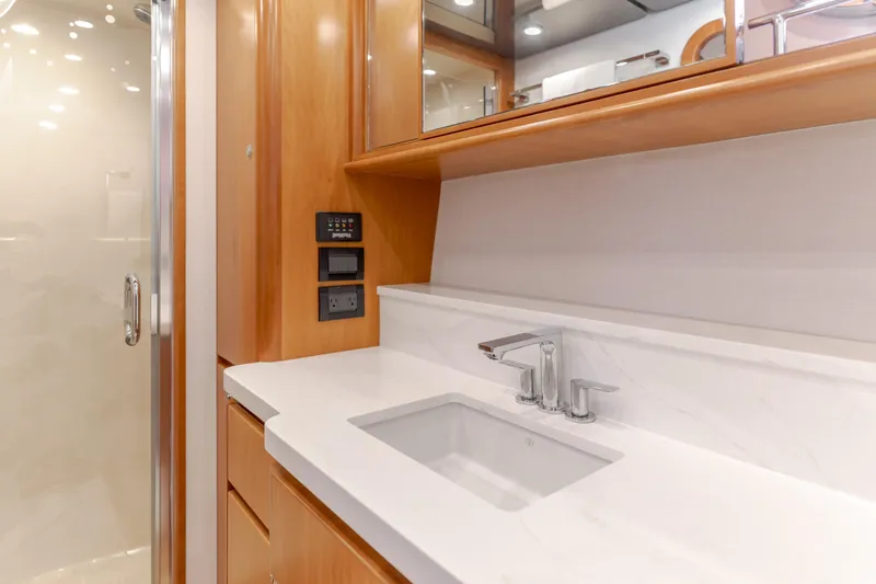 Slide: The Image of Luxurious bathroom sink area in 2006 West Bay 64 yacht, featuring modern fixtures and wood cabinetry. - 26
