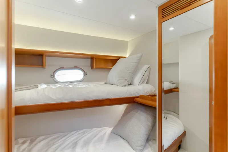 Slide: The Image of Cozy bunk beds in 2006 West Bay 64 yacht cabin with wooden accents and porthole window. - 31