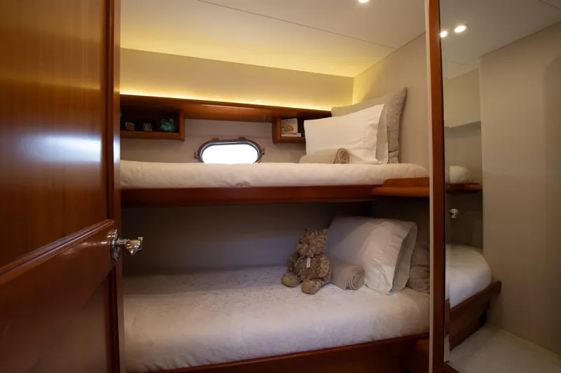 Slide: The Image of Cozy bunk bed cabin in 2006 West Bay 64 yacht, featuring plush bedding and soft lighting. - 61