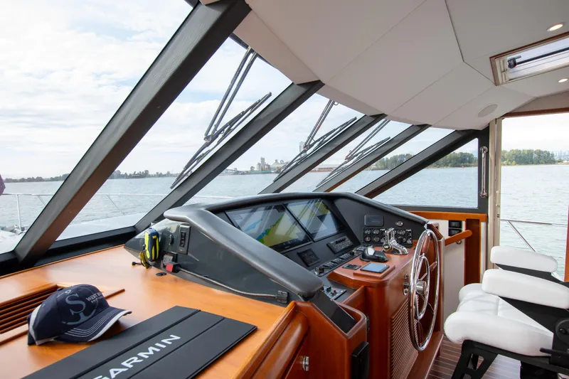 Slide: The Image of Pilothouse of 2006 West Bay 64 yacht with steering wheel, navigation equipment, and scenic water view. - 64