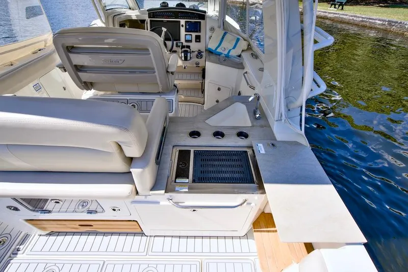 Slide: The Image of 2019 Boston Whaler 350 Realm interior with helm, seating, and outdoor kitchen by water. - 21