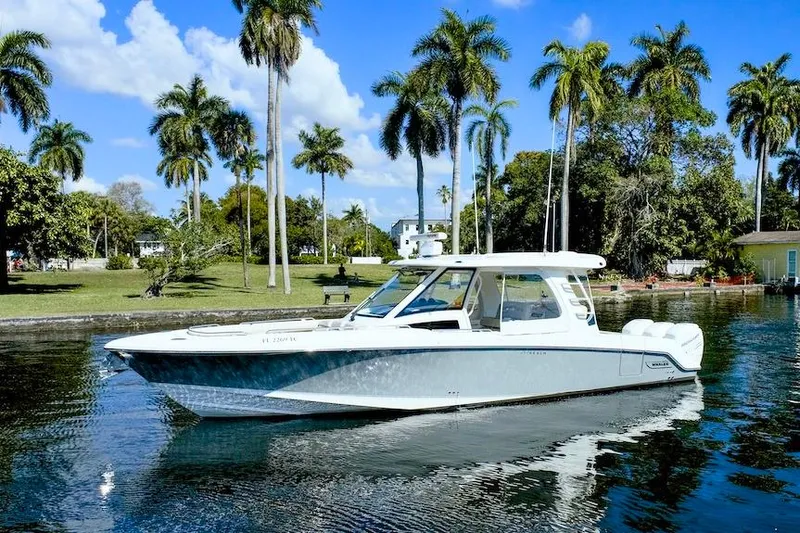 Slide: The Image of 2019 Boston Whaler 350 Realm boat on a sunny day, surrounded by palm trees. - 3