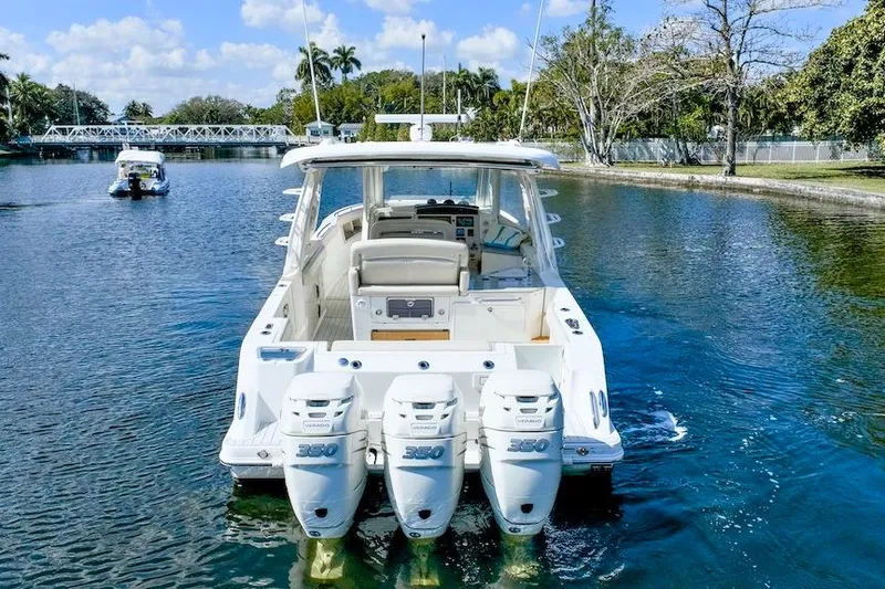 Slide: The Image of 2019 Boston Whaler 350 Realm with triple outboard engines on a scenic waterway. - 6