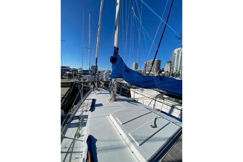 Slide: The Image of 1979 Morgan 321 sailboat docked, featuring blue sails and urban skyline backdrop. - 3