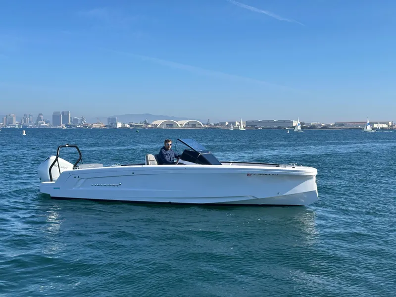 Slide: The Image of 2021 Axopar 22 Spyder boat cruising on a sunny day with city skyline in background. - 0