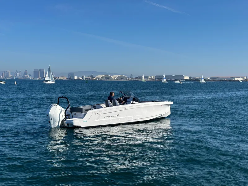 Slide: The Image of 2021 Axopar 22 Spyder boat cruising on a sunny day with city skyline in background. - 3