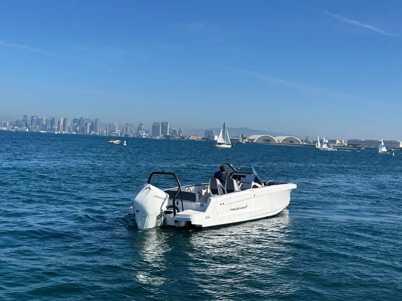 Slide: The Image of 2021 Axopar 22 Spyder boat cruising on a sunny day with city skyline in background. - 4