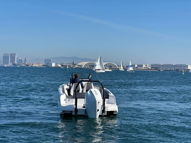Slide: The Image of 2021 Axopar 22 Spyder on open water with cityscape and sailboats in background. - 5