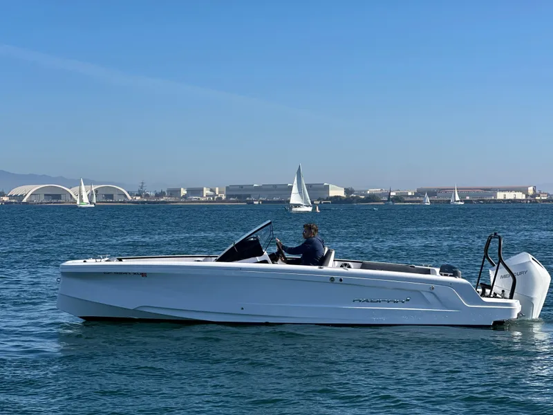 Slide: The Image of 2021 Axopar 22 Spyder boat cruising on a sunny day with sailboats in the background. - 6