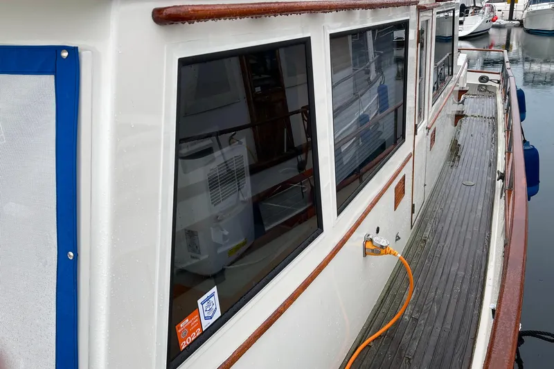 Slide: The Image of 1974 Grand Banks 42 Motoryacht docked, showcasing side view with windows and power connection. - 13