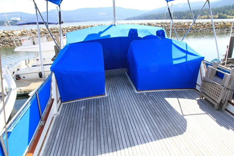 Slide: The Image of 1974 Grand Banks 42 Motoryacht deck with blue covers, docked by scenic waterfront. - 14
