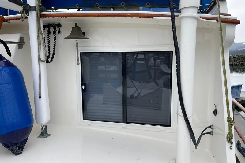 Slide: The Image of 1974 Grand Banks 42 Motoryacht deck with bell, window, and blue fender. - 15