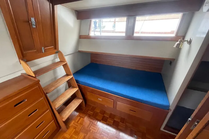Slide: The Image of 1974 Grand Banks 42 Motoryacht cabin with wooden interior, blue cushion, and storage drawers. - 39
