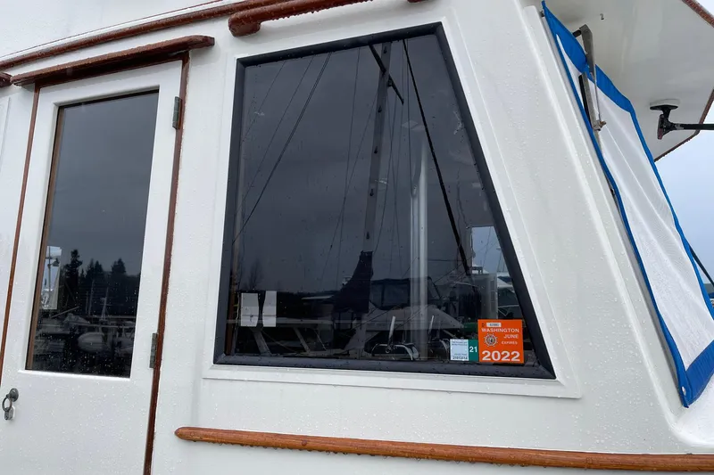 Slide: The Image of 1974 Grand Banks 42 Motoryacht exterior with window and door, displaying 2022 registration sticker. - 7