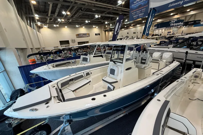 Slide: The Image of 2026 Cobia 285 Center Console boat displayed at an indoor boat show. - 1