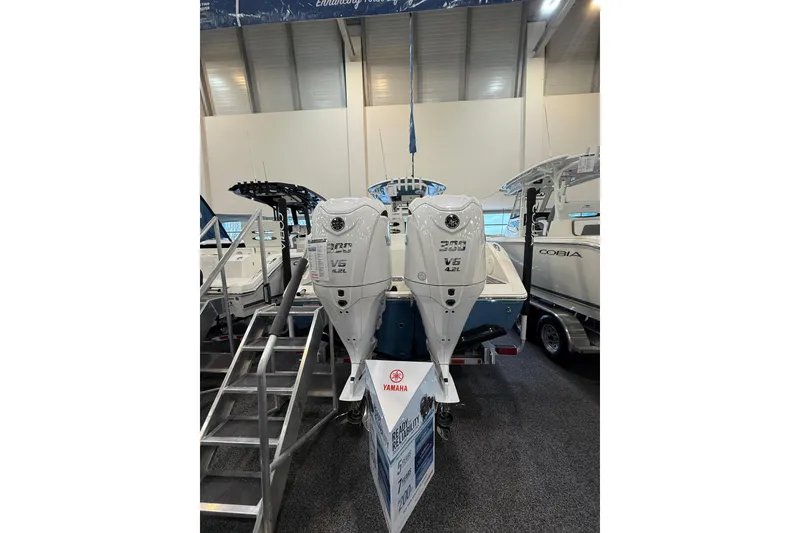 Slide: The Image of 2026 Cobia 285 Center Console with twin Yamaha V6 outboard engines displayed indoors. - 5