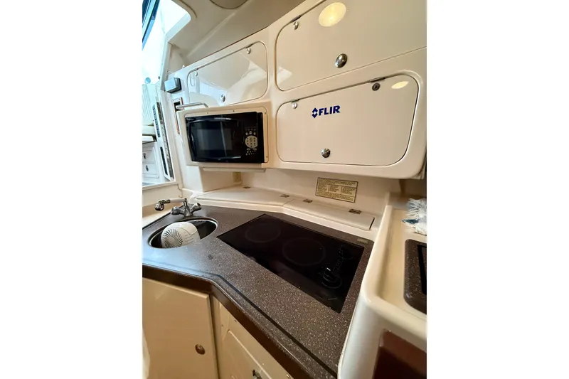 Slide: The Image of 2002 Grady-White Express 330 boat kitchen with microwave, stove, and sink. - 13