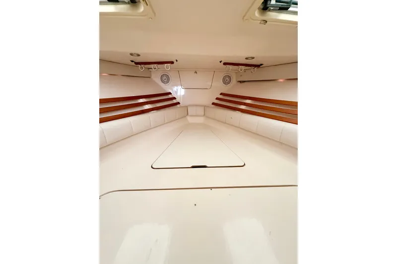 Slide: The Image of Interior cabin of 2002 Grady-White Express 330 boat, featuring white seating and wood accents. - 15