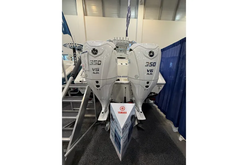 Slide: The Image of 2026 Cobia 305 Center Console with twin Yamaha 350 V6 outboard engines displayed indoors. - 2
