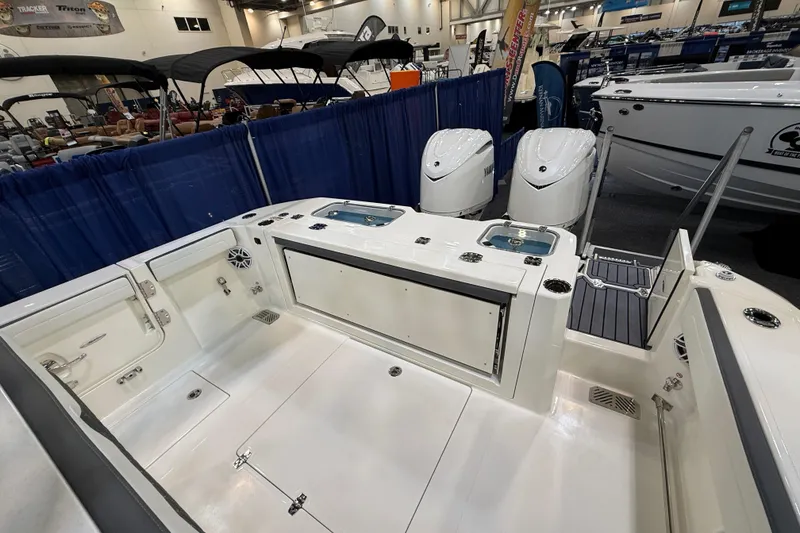 Slide: The Image of 2026 Cobia 305 Center Console boat interior at a boat show, featuring dual engines. - 8