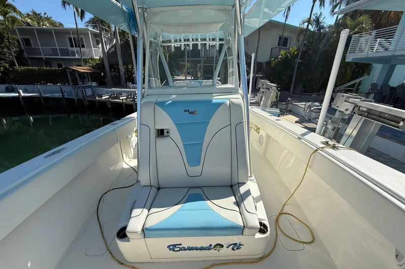 Slide: The Image of 2019 SeaVee 340Z boat interior with blue and white seating, docked near waterfront homes. - 10
