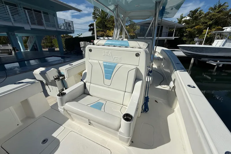 Slide: The Image of 2019 SeaVee 340Z boat interior with white and blue seating, docked near modern homes. - 5