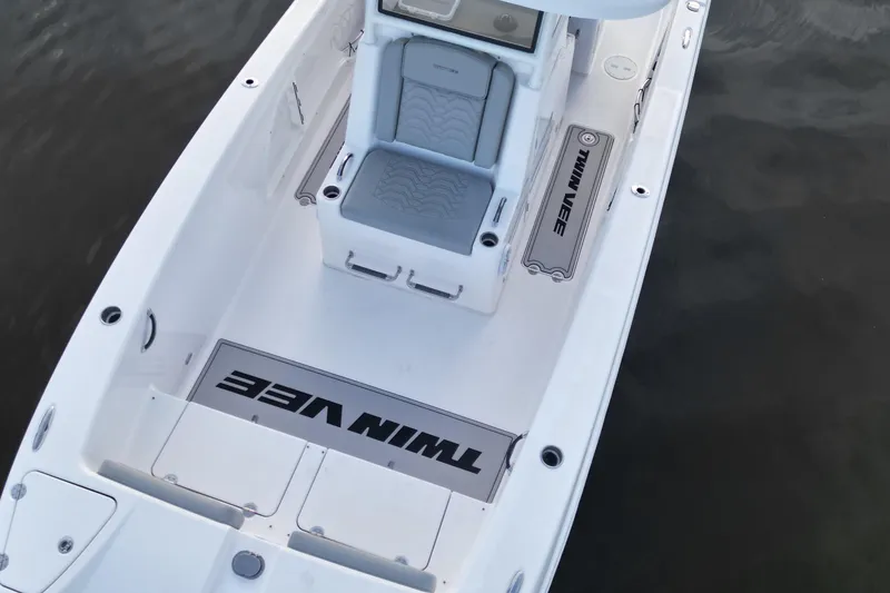 Slide: The Image of 2023 Twin Vee 260 GFX CC boat interior with seating and branding, on calm water. - 10