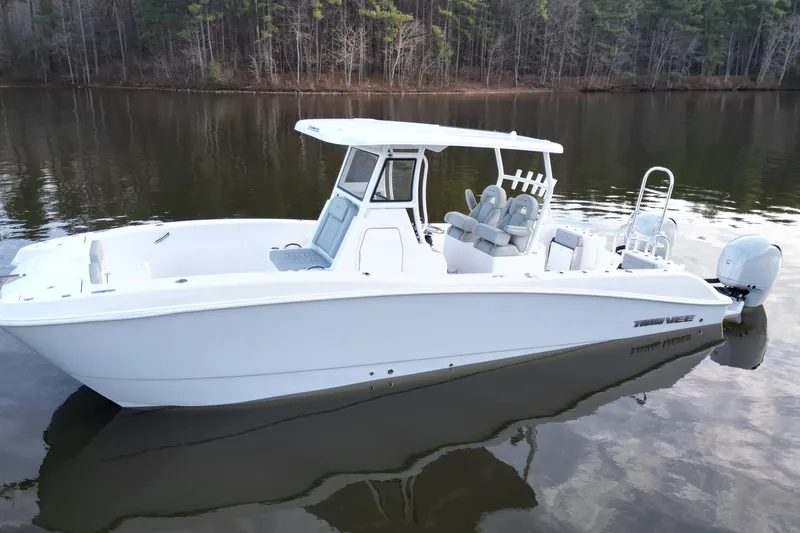 Slide: The Image of 2023 Twin Vee 260 GFX CC boat on calm lake with forest backdrop. - 16
