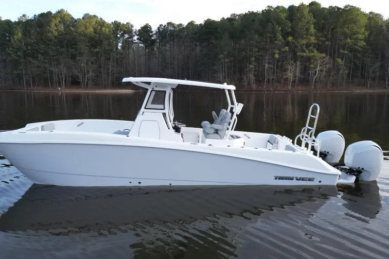 Slide: The Image of 2023 Twin Vee 260 GFX CC boat on calm lake with forest backdrop. - 2