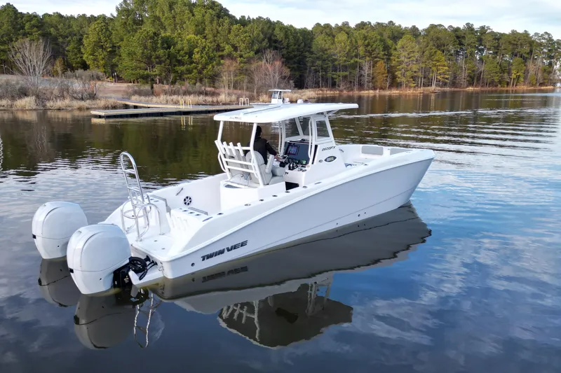 Slide: The Image of 2023 Twin Vee 260 GFX CC boat on calm lake with forested shoreline. - 22