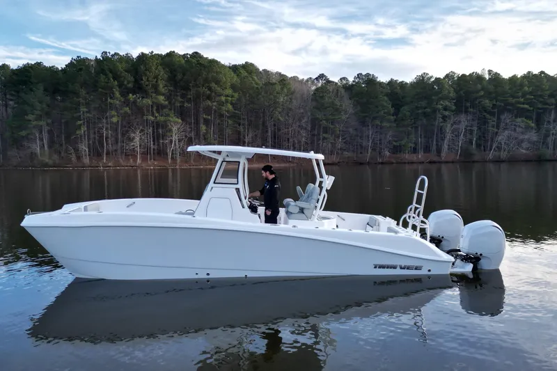 Slide: The Image of 2023 Twin Vee 260 GFX CC boat on calm lake with forest backdrop. - 24