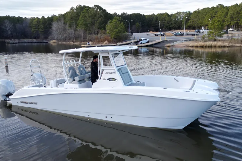 Slide: The Image of 2023 Twin Vee 260 GFX CC boat on calm water near a wooded shoreline. - 26