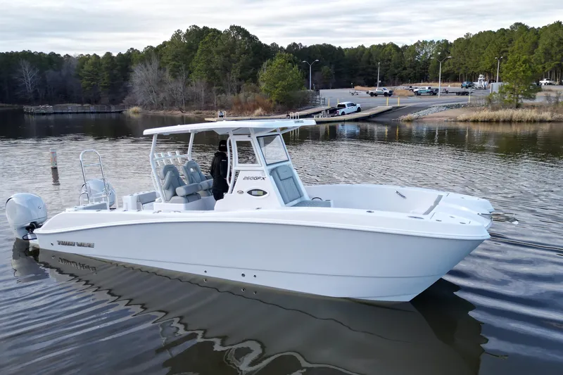Slide: The Image of 2023 Twin Vee 260 GFX CC boat on calm lake with forested shoreline. - 27
